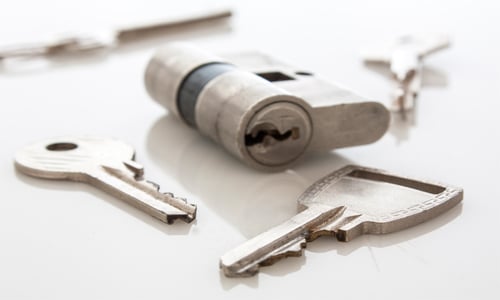 door lock cylinder with several keys on table